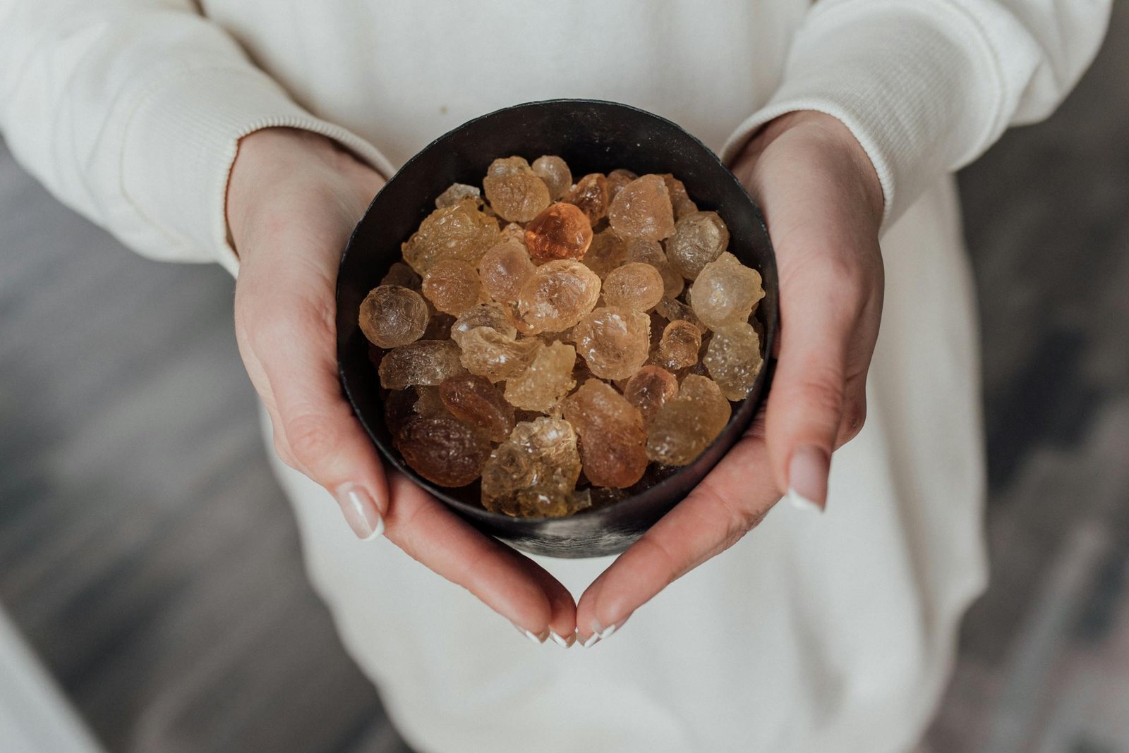 A close-up view of hands holding a bowl of natural healing crystals.