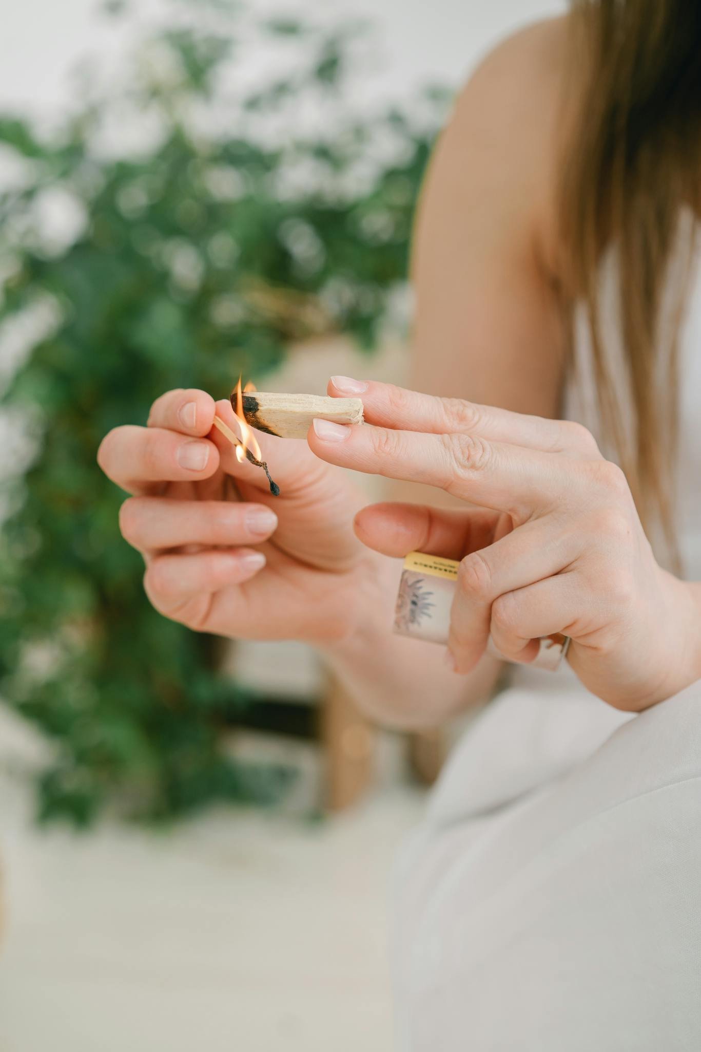 A woman lights sage for a calming meditation ritual, promoting relaxation and mindfulness.